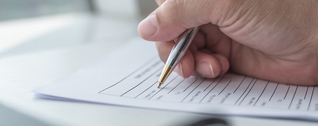 Close up of person filling in personal details onto paper form